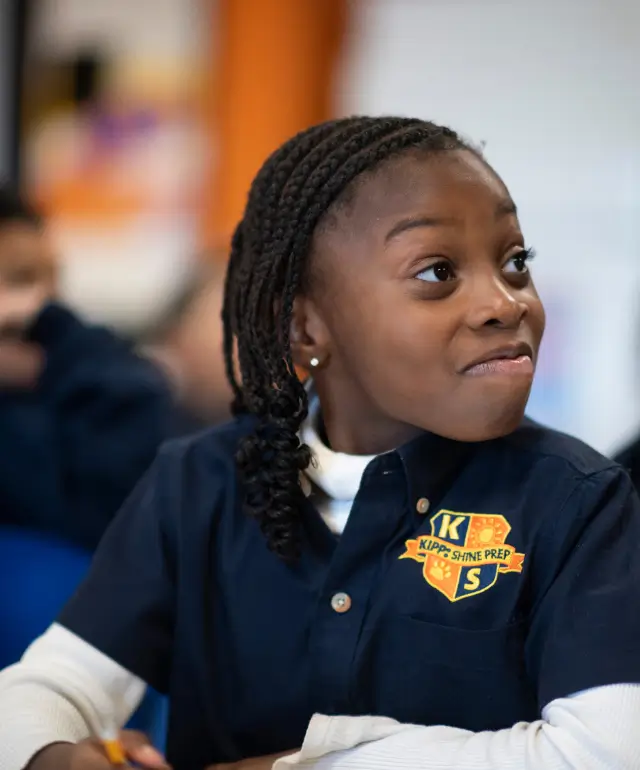 Cute young lady listening to her teacher at KIPP