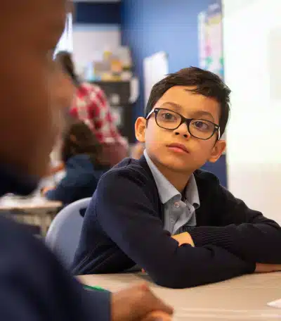Kid with glasses listening to his class friend