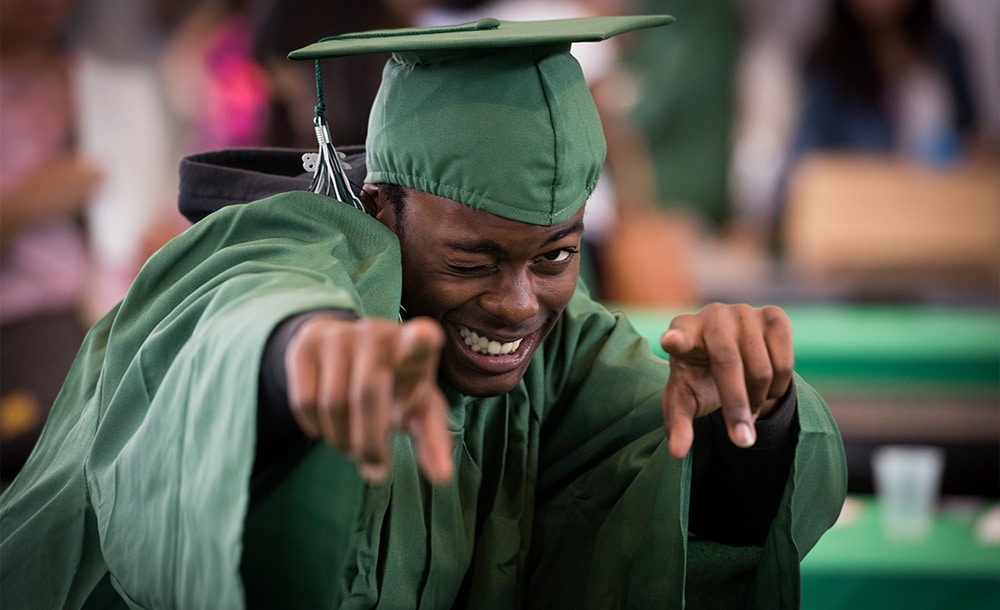 student graduating and pointing at camera winking