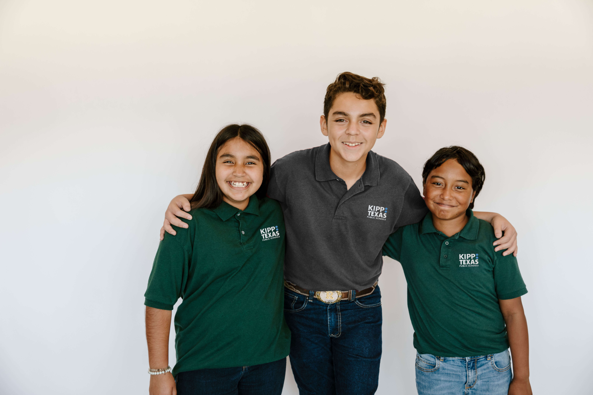 three children smiling with KIPP: Texas shirts on