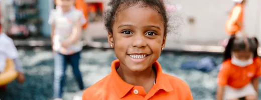 Young girl in orange school suit smiling
