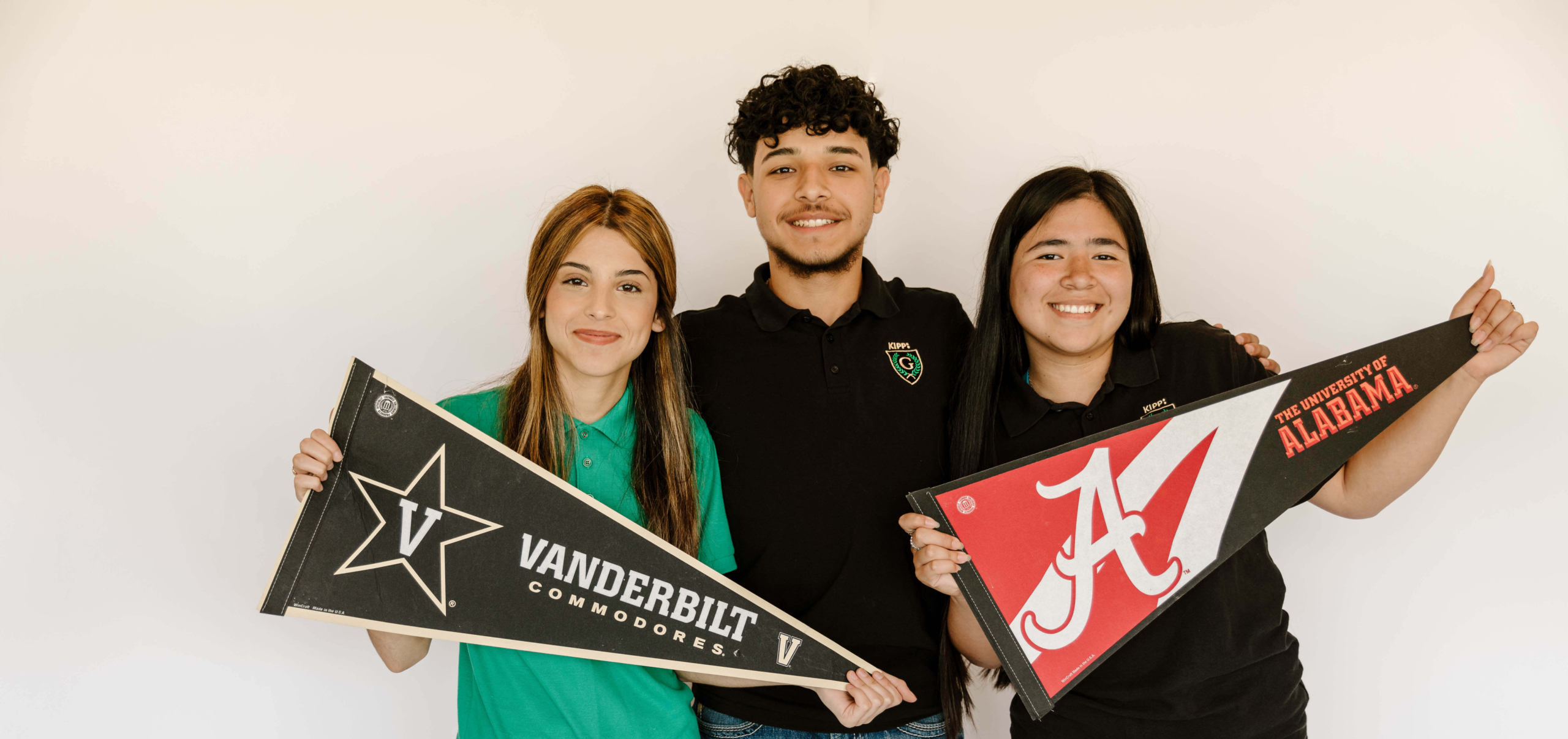 Tres estudiantes de secundaria de KIPP Texas - San Antonio sosteniendo pancartas universitarias