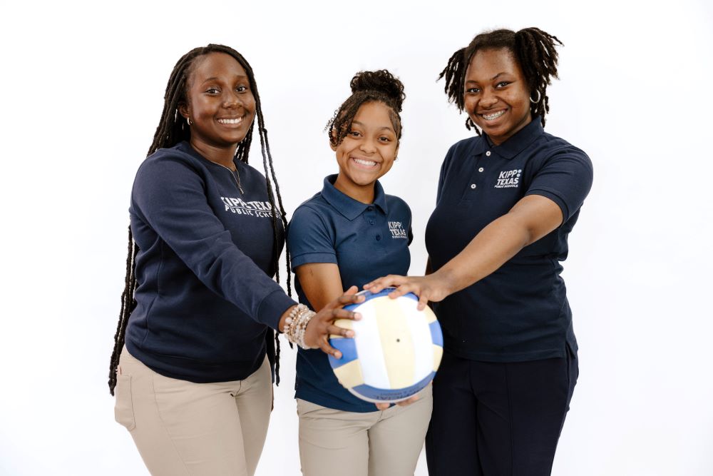 Three KIPP Texas Middle School Students Holding a Volleyball